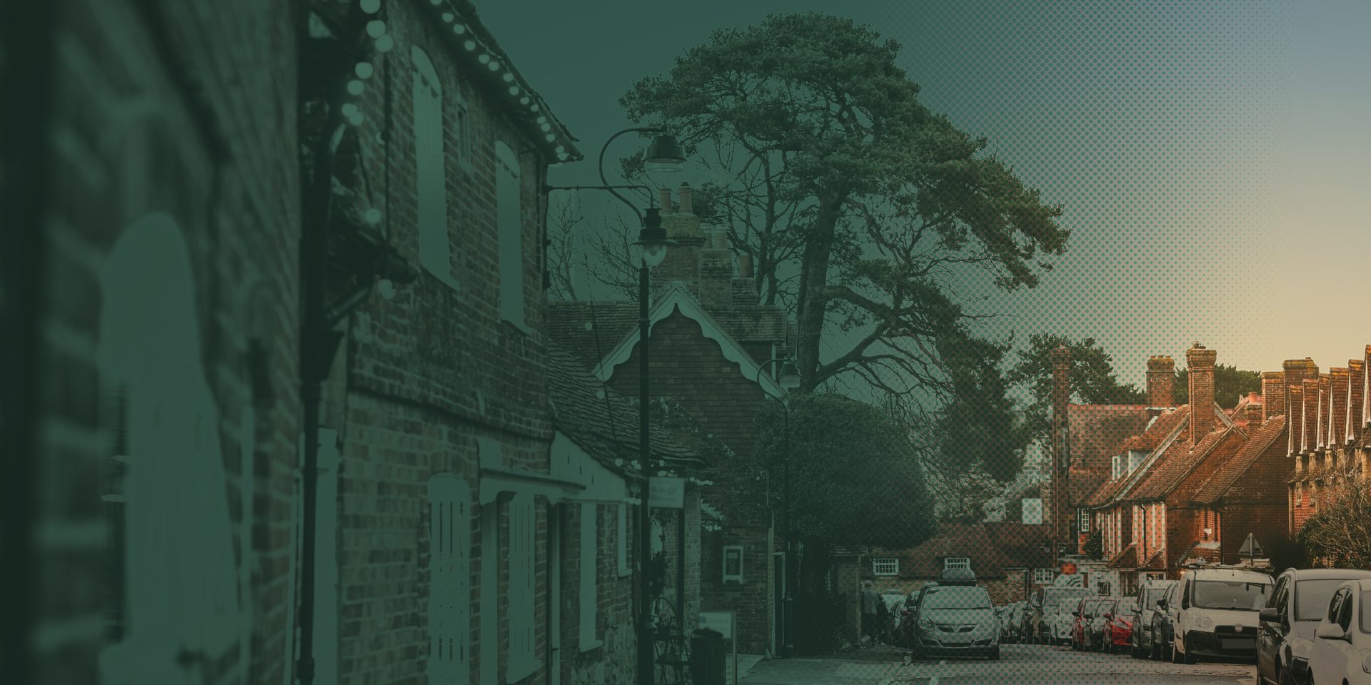A red-brick market-town high street with a tall Scots pine and terraced cottages in late-afternoon light